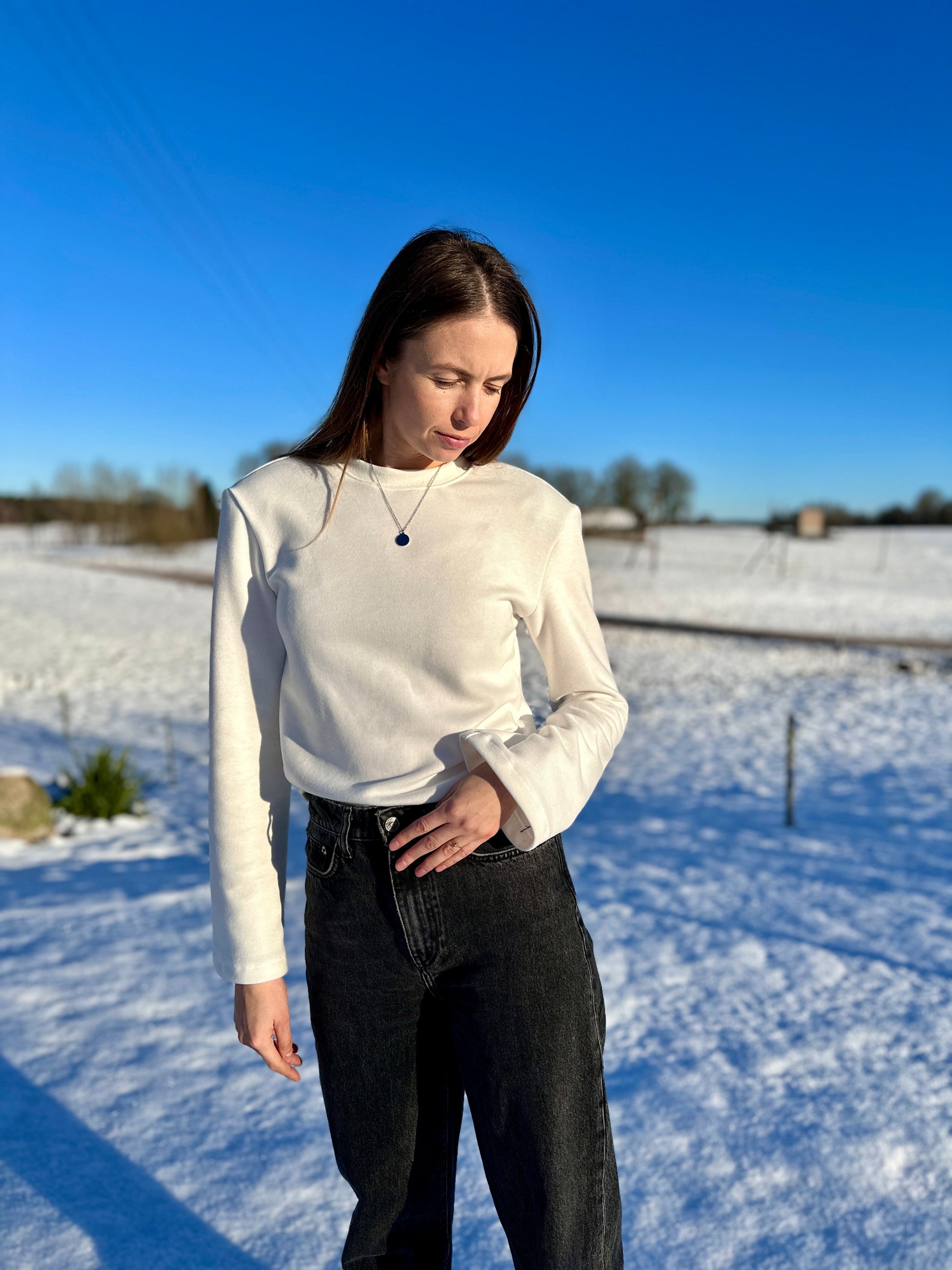 Prigludusi megzto trikotažo palaidinė ilgomis platėjančiomis rankovėmis su petukais “Balta”